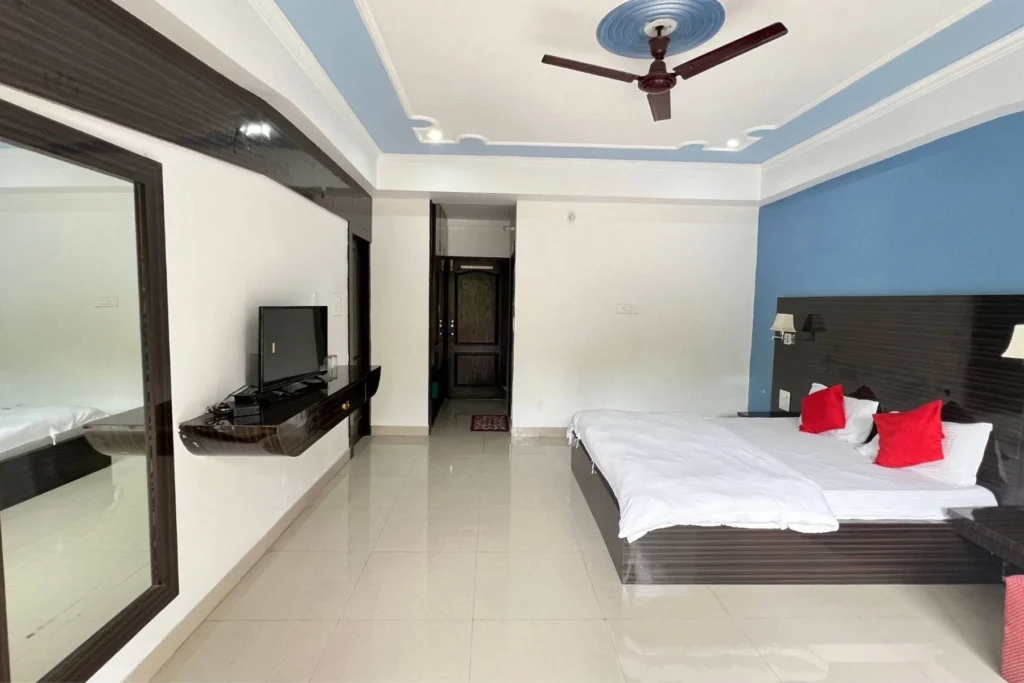 Spacious deluxe room with a large bed, bright lighting, and modern interiors.